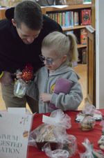 a child and her father look at a piece of food