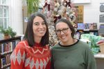 two people pose in front of a Christmas tree