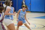 a child wearing a blue uniform dribbling a basketball