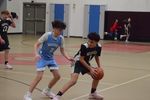 a child in a blue uniform tries to take a ball from a child in a green uniform
