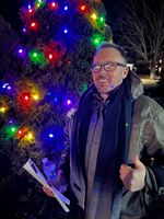 a man poses by a Christmas tree