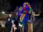 several people posing in front of a Christmas tree