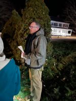 a man speaking in front of a tree