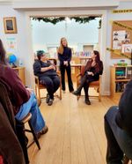 people in a meeting room listen to a woman speak