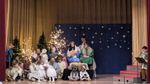 children and a few adults in costumes in front of Christmas decor