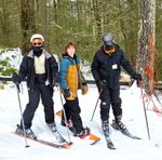 3 scouts in ski gear and on skis in a forest