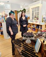 two women look at a stack of cupcakes
