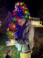 a man in front of a Christmas tree with lights