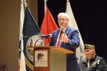 a man speaks at a podium in front of flags