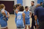 several children in blue uniforms with an adult; a referee is in the background