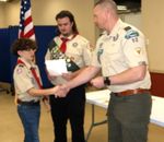 a scout receiving awards from adult scout leaders
