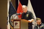 a man speaks at a podium in front of flags