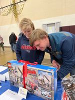 two people writing their bid for a Lego set; the Lego set is on the table