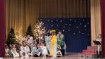 children and a few adults in costumes in front of Christmas decor