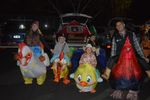 a group of people in chicken costumes with an open car trunk